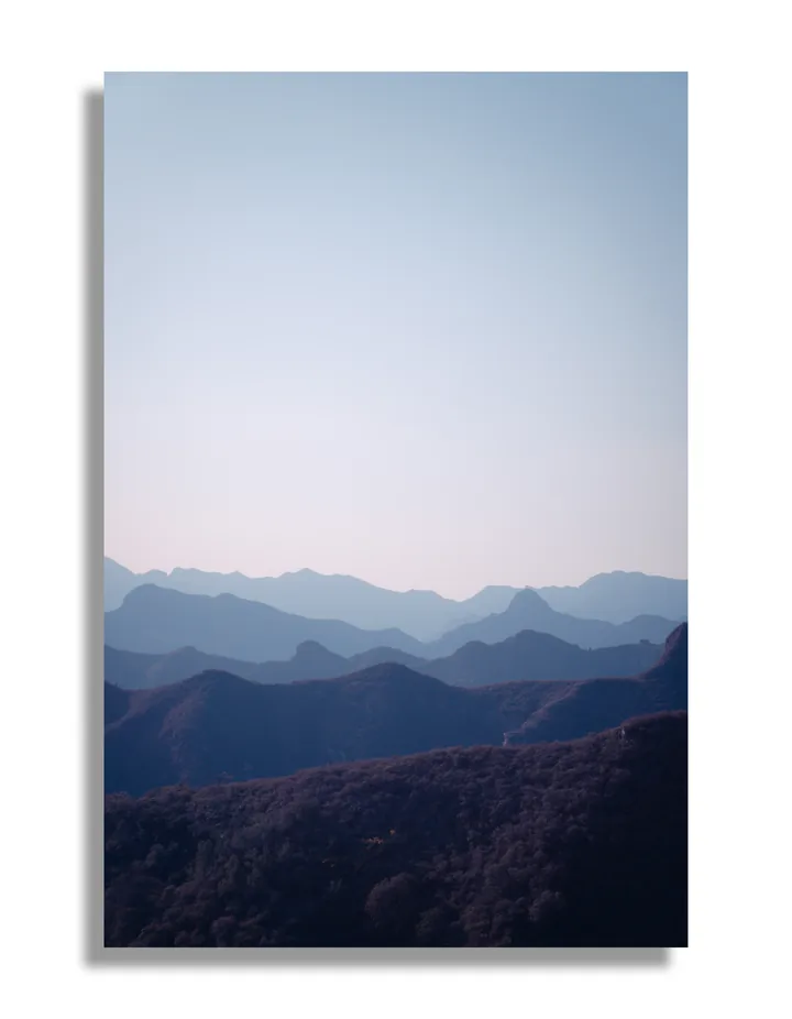 Layers of mountain ridges beneath a pale blue sky