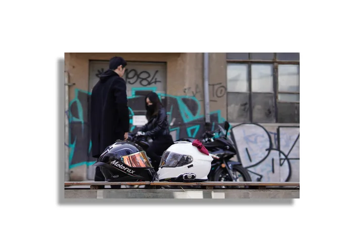 People and motorcycles beside a graffiti-covered wall