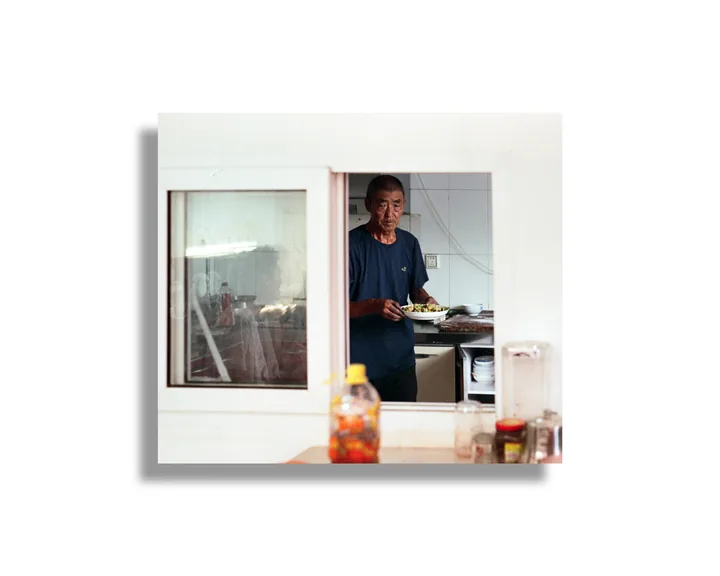 A man holding a plate at a kitchen window