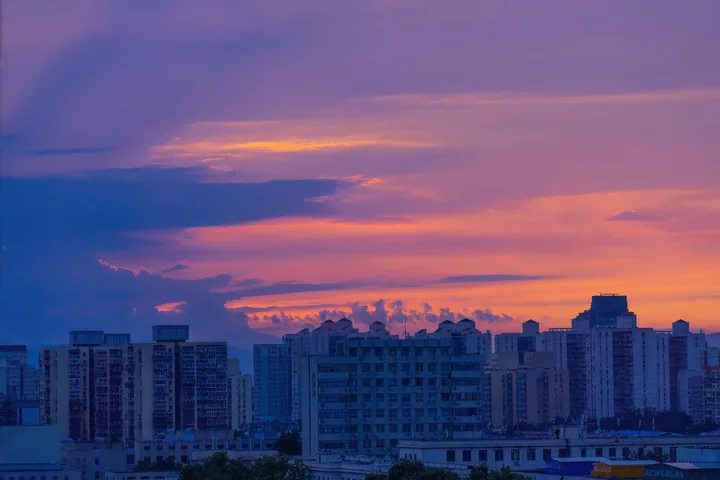 Pink and purple sunset clouds over city buildings