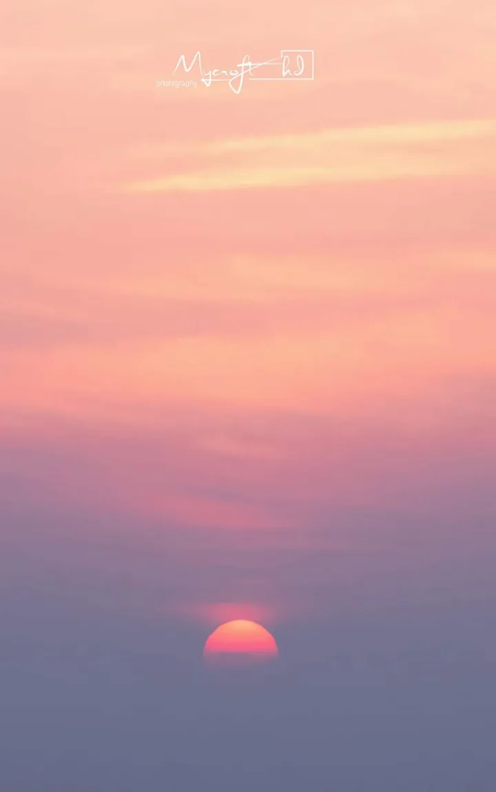 Sun low on the horizon under a pink sky
