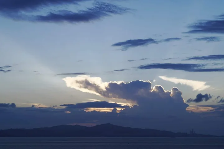 Sunbeams around a dark cloud over distant mountains