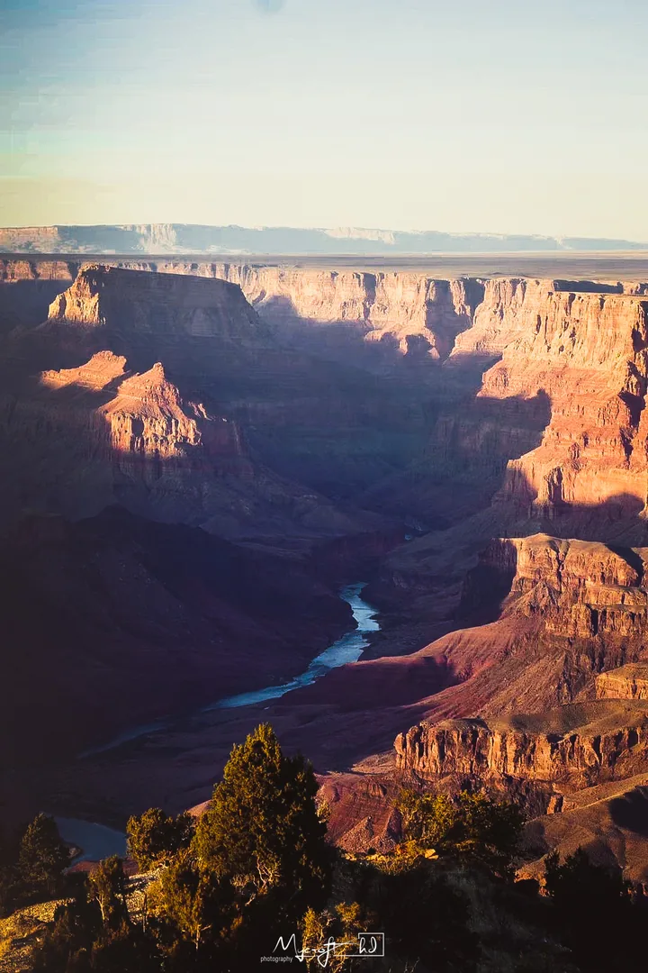 Sunlit cliffs and a river winding through a canyon