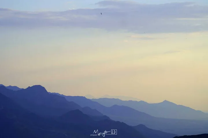 Layers of blue mountains beneath a pale sky