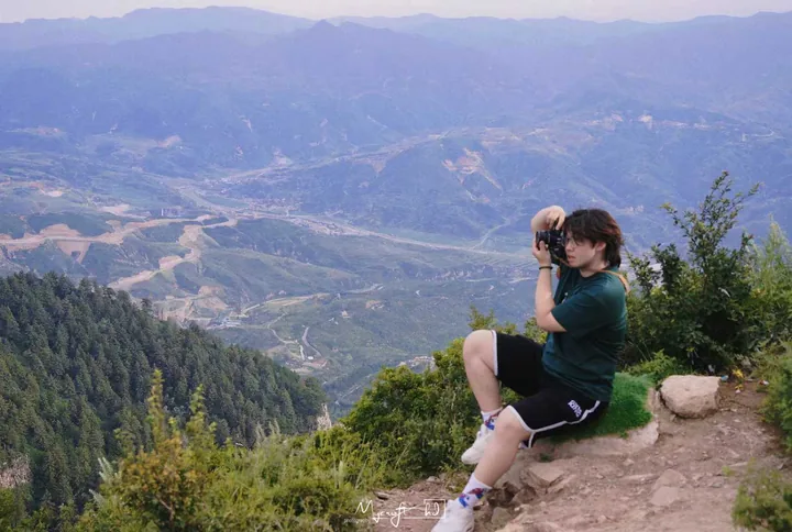 Person photographing mountains from a rocky overlook