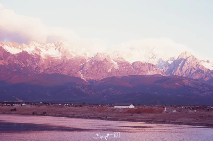 Pink light across snowy mountains and an open plain