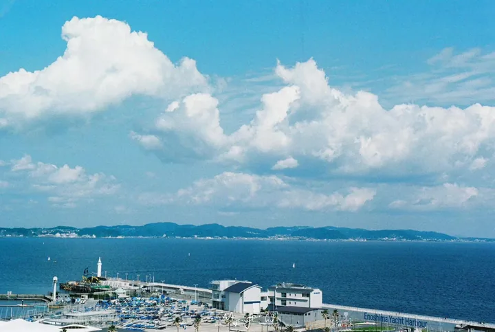 Harbor buildings and blue water beneath billowing clouds